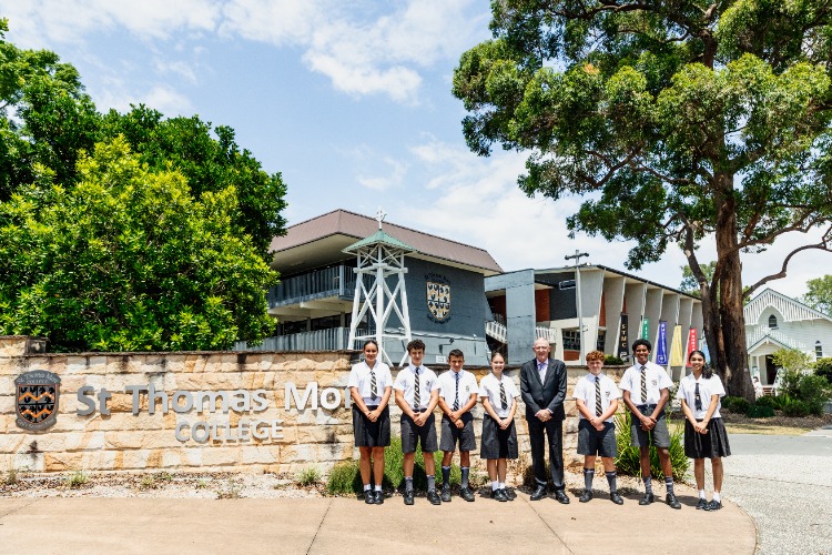 college principal with students at front gates